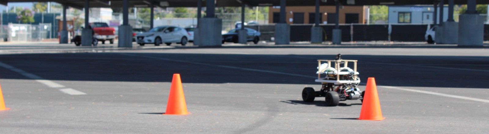 The self-driving RC car on a parking-lot course between orange cones.